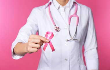 Pembe kurdele ve beyaz arka planda, closeup stetoskop ile kadın doktor. Meme kanseri kavramı
