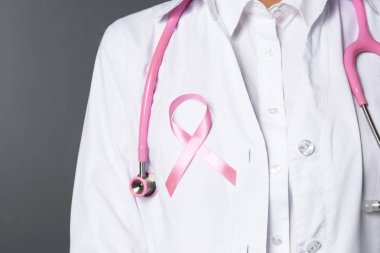 Pembe kurdele ve beyaz arka planda, closeup stetoskop ile kadın doktor. Meme kanseri kavramı
