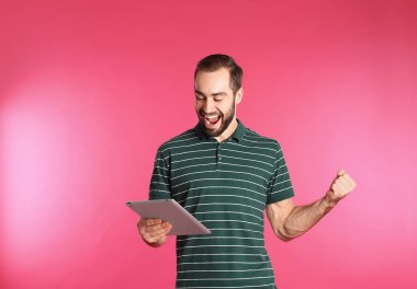 Renk arka plan üzerinde zaferini kutluyor tablet ile duygusal genç adam