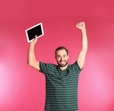Renk arka plan üzerinde zaferini kutluyor tablet ile duygusal genç adam