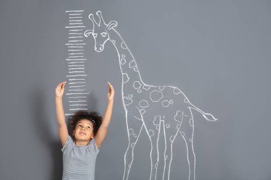 Afro-Amerikan çocuk gri arka plan üzerinde çizim tebeşir zürafa yakınındaki yükseklik ölçme