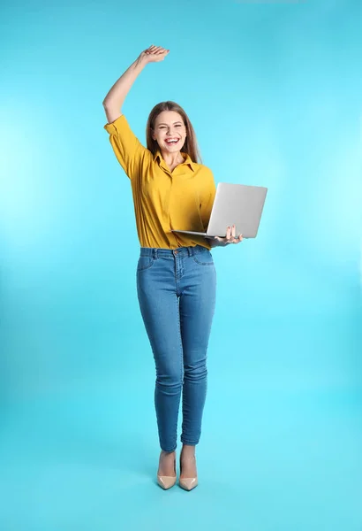 情感年轻的妇女与笔记本电脑庆祝胜利在颜色背景 — 图库照片