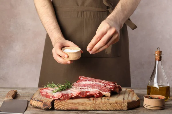 Man salting fresh raw meat on table against grey background, closeup — Stock Image Man Salting Fresh Raw Meat Table Grey Background Closeup Royalty Free Stock Images