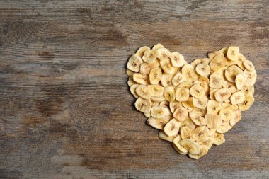 Kalp şekli tatlı muz dilimleri ahşap arka plan, üstten görünüm üzerinde yapılır. Kurutulmuş meyve sağlıklı çerez olarak