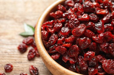 Bowl with cranberries on wooden table, closeup. Dried fruit as healthy snack