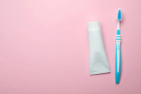 Blank tube of toothpaste and brush on color background, top view with space for text