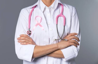 Pembe kurdele ve gri arka plan, closeup stetoskop ile kadın doktor. Meme kanseri kavramı