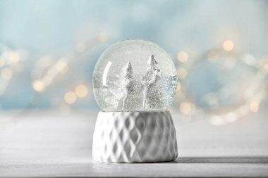 Snow globe with deer and trees on blurred background