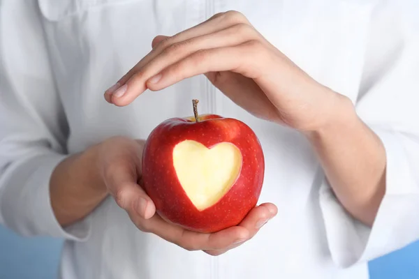 Woman holding apple with carved heart, closeup