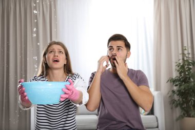 Onun kocası arama tesisatçı oturma odasında iken tavandan sızıntı su toplama duygusal genç kadın
