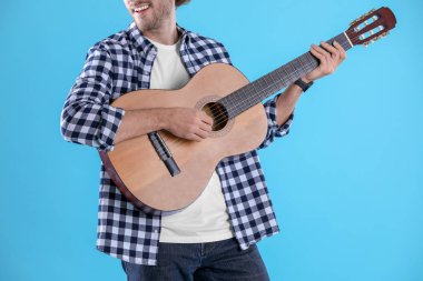 Genç adam renk arka plan üzerinde akustik gitar çalmak