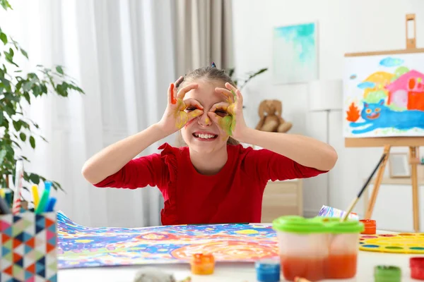 屋内のテーブルで塗られた手でメガネを作る小さな子供 — ストック写真