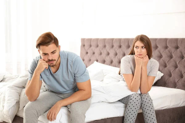 Upset young couple with relationship problems in bedroom