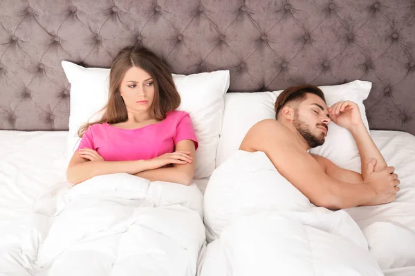 不安的年轻女子躺在床上靠近她熟睡的丈夫在家里 关系问题 — 图库照片