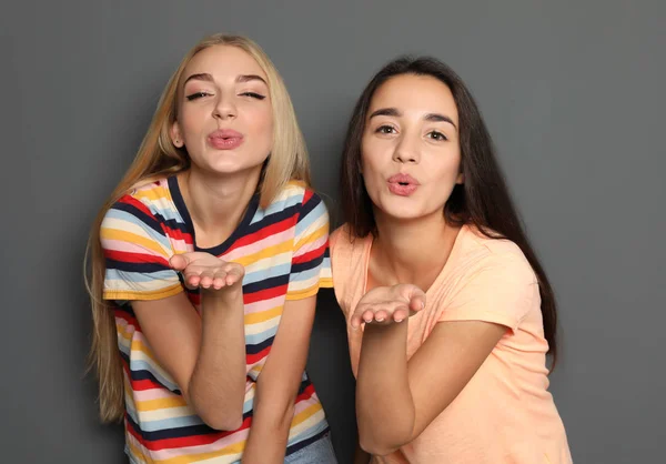 Beautiful women sending air kisses against gray background