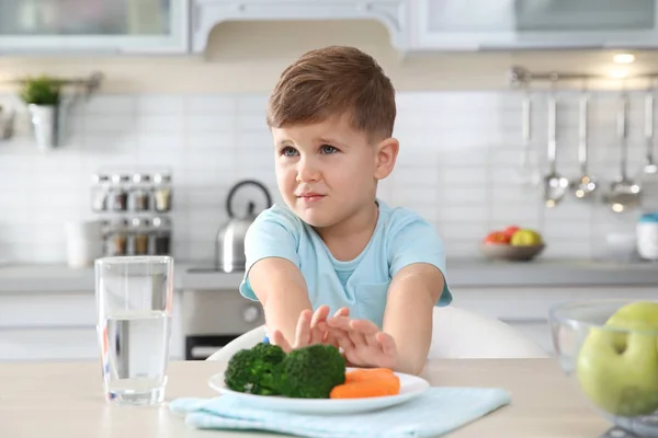可爱的小男孩拒绝在厨房的桌子上吃蔬菜 — 图库照片