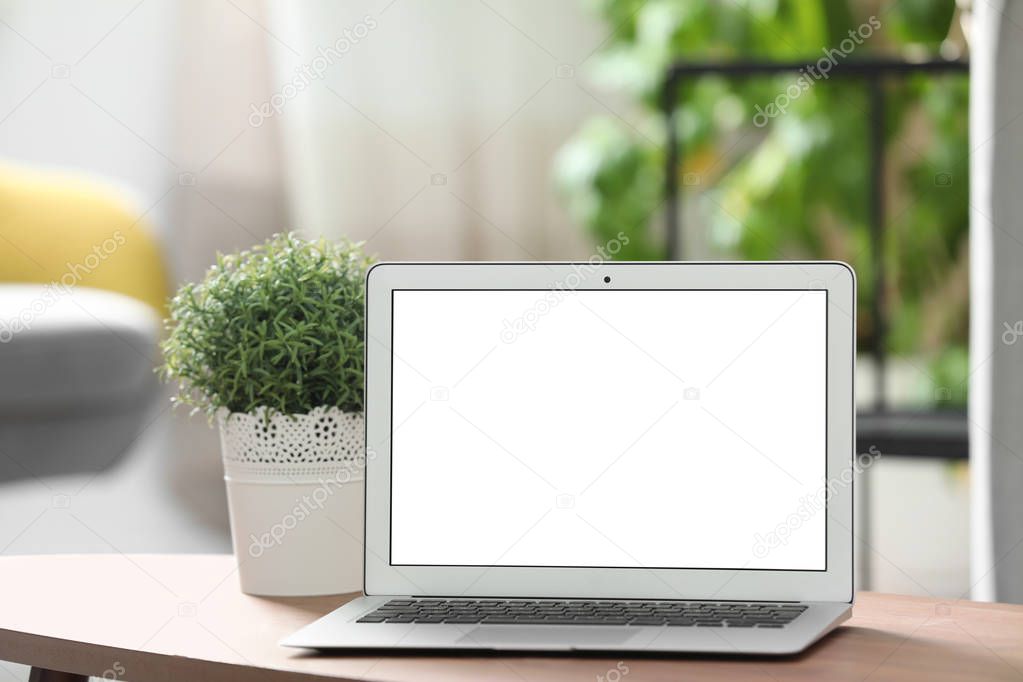 Laptop with blank screen on table indoors. Space for text