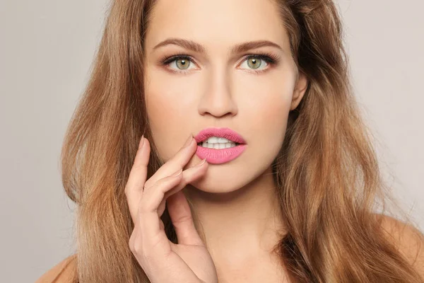 Genç kadın gri arka plan üzerinde güzel ruj var