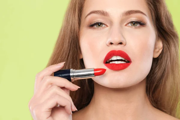 Mujer Joven Aplicando Lápiz Labial Rojo Sobre Fondo Color —  Fotos de Stock