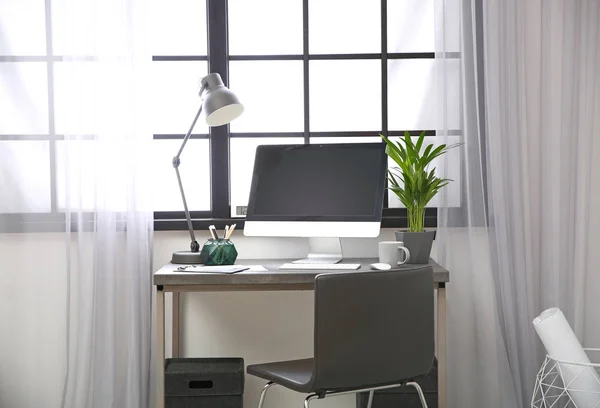 Stylish workplace with computer near window at home office. Space for text