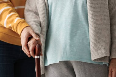Yürüyüş baston ve dişi bakıcı, closeup görünümü ile yaşlı kadın