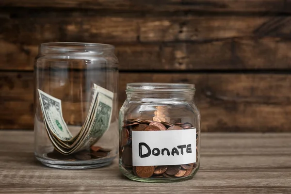 Donation jars with money on wooden table