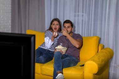 Oturma odasında kanepede birlikte Tv izlerken patlamış mısır ile çift