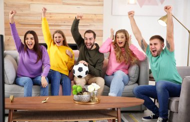 Grup arkadaşıyla birlikte oturma odasında favori futbol takımının zaferini kutluyor