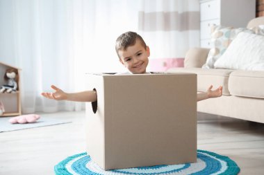 Oturma odasında karton uçak ile oynayan sevimli küçük kız