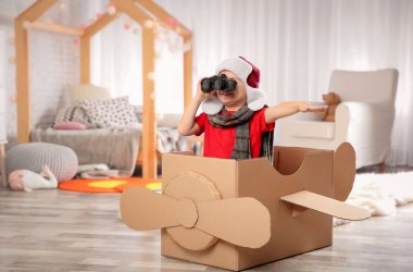 Oturma odasında karton uçak ile oynayan sevimli küçük kız