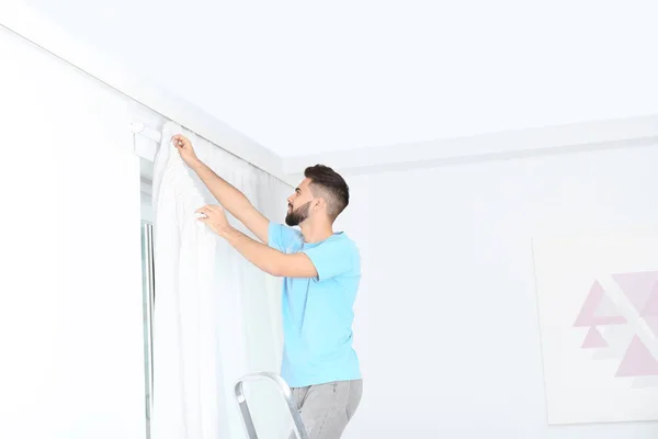 Joven Guapo Hombre Colgando Cortina Ventana Habitación —  Fotos de Stock