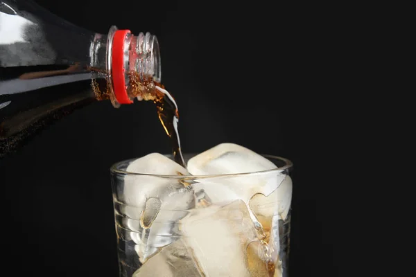 黒の背景 クローズ アップに氷とグラスにボトルからコーラを更新を注ぐ — ストック写真