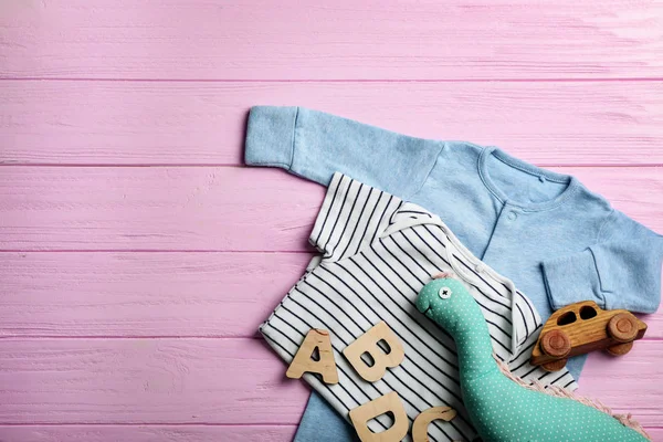 Düz yatıyordu kompozisyon ile şirin kıyafetleri ve ahşap arka plan üzerinde metin için yer. Bebek Aksesuarları