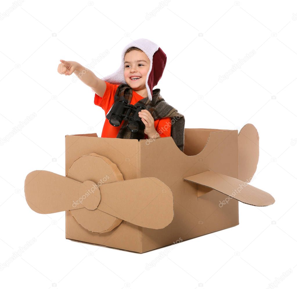 Cute little boy playing with binoculars and cardboard airplane on white background