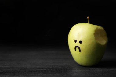 Isırıldı elma mutsuz yüz çizim koyu arka plan karşı tablo, metin için yer ile. Depresyon belirtileri