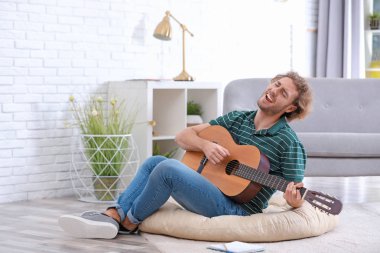 Elektro gitar çalmak oturma odasında genç adam. Metin için yer