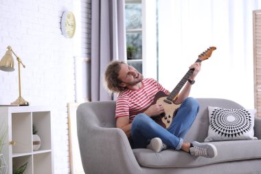 Elektro gitar çalmak oturma odasında genç adam. Metin için yer