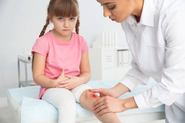 Kadın doktor küçük kızın inceleyerek klinik bacağından yaralandı. İlk yardım