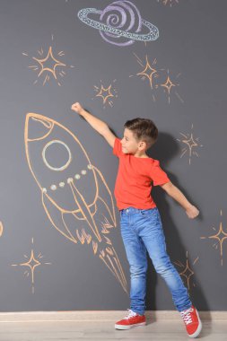 Tebeşir roket gri duvara çizim ile oynayan sevimli küçük çocuk