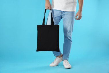 Tekstil çanta renk arka plan, closeup üzerinde tutan genç adam. Mockup tasarım için