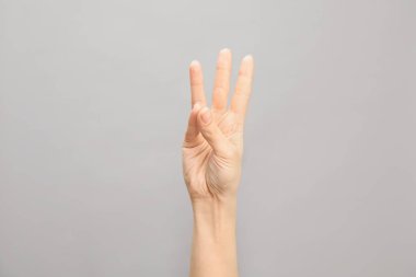 Gösterilen kadın altı gri arka plan, closeup üzerinde numara. İşaret dili