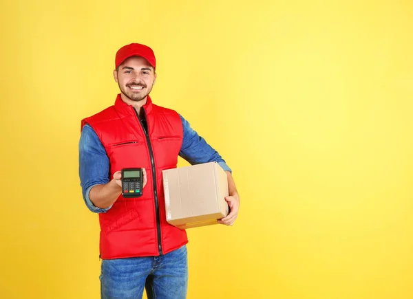 Male courier with parcel and payment terminal on color background. Space for text