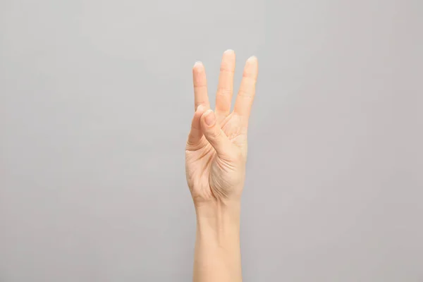 Woman showing number six on grey background, closeup. Sign language