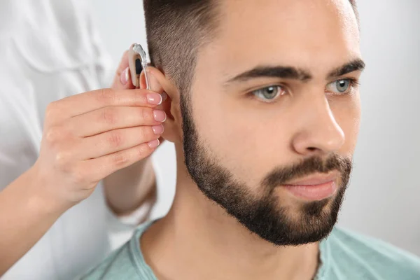 耳鼻喉科医生把助听器放在人的耳朵在白色背景 — 图库照片