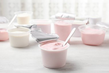 Plastik bardak taze yoğurt ve beyaz ahşap masa kaşık ile