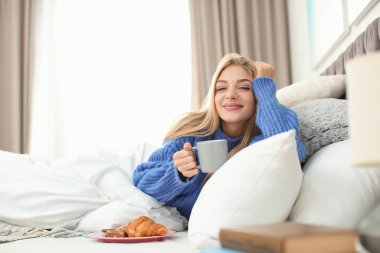 Evde yatakta kahvaltı ile yalan güzel ve genç birbayan. Kış atmosfer