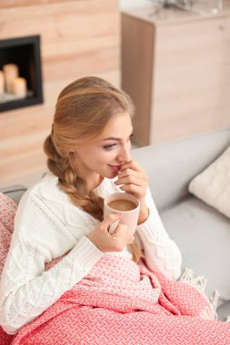Evde Kupası ile kanepede oturan güzel ve genç birbayan. Kış atmosfer