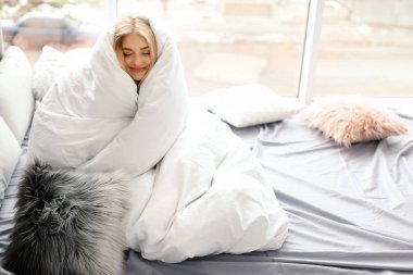 Güzel ve genç birbayan yumuşak battaniye oturma pencere evde yakınındaki sarılı. Kış atmosfer