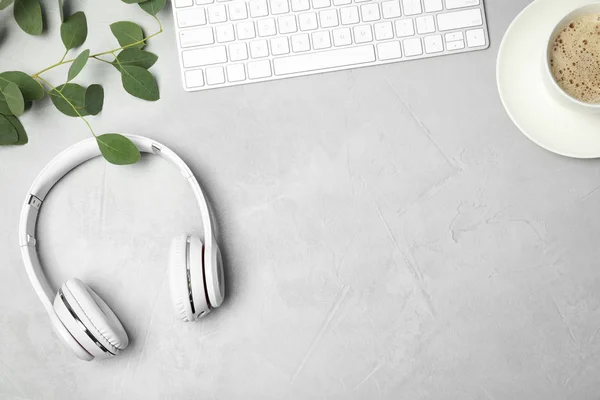Flat lay composition with headphones, computer keyboard and space for text on grey background