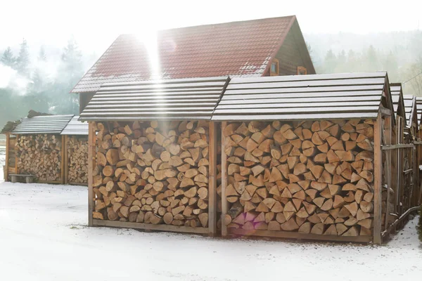 Wood sheds with stacked firewood outdoors on sunny winter day